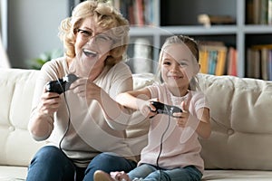 Modern grandmother play computer game with small granddaughter photo