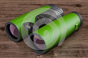 Modern green binoculars on the wooden background. 3D rendering photo