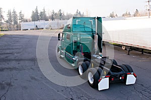 Modern green semi truck tractor driving on parking lot for attaching trailer