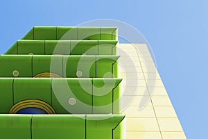 Modern green and yellow building with balconies on blue sky background.