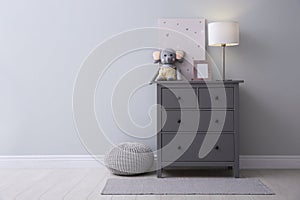 Modern grey chest of drawers near wall in child room, space for text. Interior design