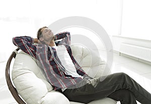 Modern guy is resting sitting in a large comfortable chair. side view.