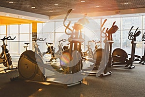 Modern gym interior with equipment, fitness exercise elliptical trainers