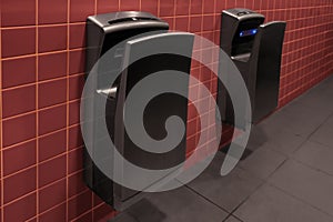 Modern hand dryers on tiled wall in public toilet
