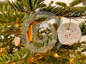 Modern handmade terrazzo christmas ball hanging in the christmas tree. Bokeh background