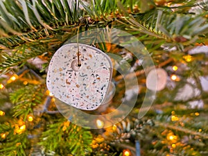 Modern handmade terrazzo christmas ball hanging in the christmas tree. Bokeh background