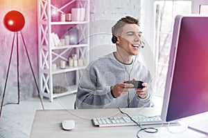 Modern handsome student fond of video games feeling joyful while playing