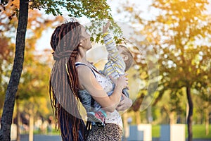 Modern happy mom with baby son walking in Sunny Park. Joy of motherhood and autumn mood