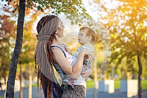 Modern happy mom with baby son walking in Sunny Park. Joy of motherhood and autumn mood