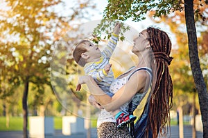 Modern happy mom with baby son walking in Sunny Park. Joy of motherhood and autumn mood