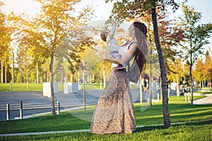 Modern happy mom with baby son walking in Sunny Park. Joy of motherhood and autumn mood