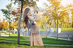 Modern happy mom with baby son walking in Sunny Park. Joy of motherhood and autumn mood