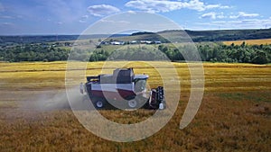 Modern harvest velhice combine tractor harvester harvests crops in the field, aerial fly orbit.