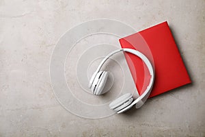 Modern headphones with hardcover book on grey background, top view.