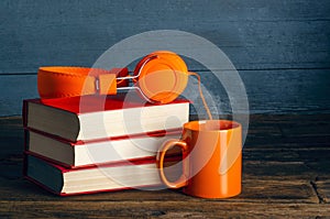 Modern headphones with stack of books and cup mug of tea coffee