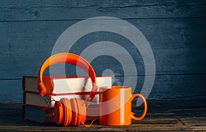 Modern headphones with stack of books and cup mug of tea coffee