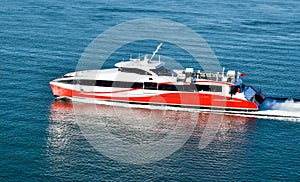 A modern high-speed catamaran ferry travels fast across the sea