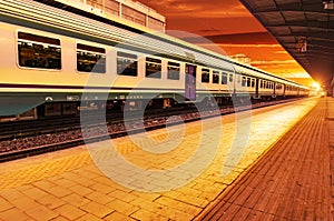 Modern high speed commuter train at the railway station at colorful sunset with vintage toning