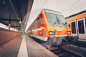 Modern high speed red commuter train at colorful sunset