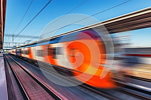 Modern high-speed train moves fast along the platform.