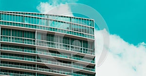 Modern highrise glass building under a blue sky with fluffy clouds