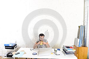 Modern hipster style student or businessman working with laptop computer at home office drinking coffee cup