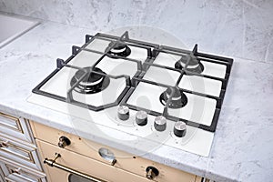 Modern hob gas stove made of tempered white glass using natural gas or propane for cooking products on light countertop in kitchen