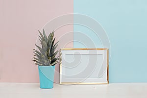 Modern home decor mock up with gold blank photo frame and tropical plant on pink blue background