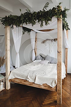 Modern home interior design. Bed with wooden canopy and pillows, blanket. Bedroom interior, scandinavian style. Home decor.