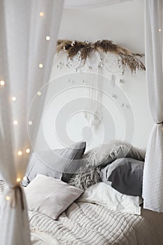 Modern home interior design. Cozy bed with wooden canopy and pillows, blanket. Bedroom interior, scandinavian style.