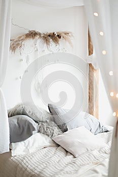 Modern home interior design. Cozy bed with wooden canopy and pillows, blanket. Bedroom interior, scandinavian style.