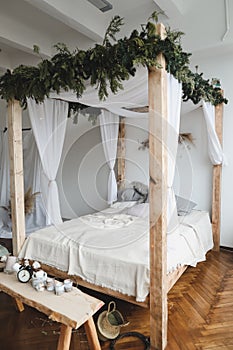 Modern home interior design. Cozy bed with wooden canopy and pillows, blanket. Bedroom interior, scandinavian style.