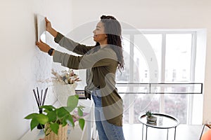 Black woman hanging picture frame on the wall