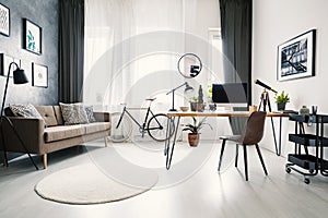 Modern home office interior with a big window, sofa, bike and de