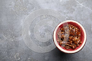 Modern hookah bowl with tobacco on grey table, top view. Space for text