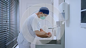 In the modern hospital in operation room in front of the camera doctor surgeon before start the surgery washing hands