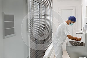 In the modern hospital in operation room in front of the camera doctor surgeon before start the surgery washing hands