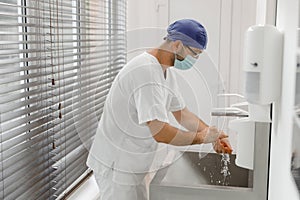 In the modern hospital in operation room in front of the camera doctor surgeon before start the surgery washing hands