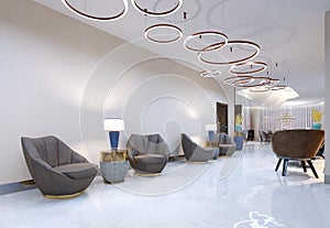 A modern hotel with a reception area and lounge with large upholstered designer chairs and a large chandelier of golden rings