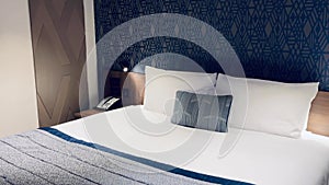 Modern hotel room, contemporary art deco design, with a geometric patterned wallpaper and bed with a decorative pillow