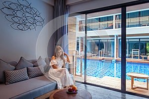 Modern hotel room with swimming pool and grey sofa.