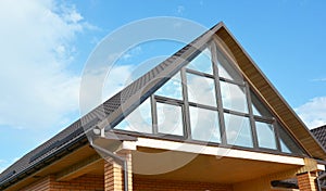 Modern house attic construction with roof guttering and panoramic mansard, attic skylight window. Attic skylight glass wall.