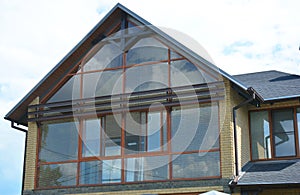 Modern house attic construction with roof guttering and panoramic mansard, attic skylight window. Attic skylight glass wall