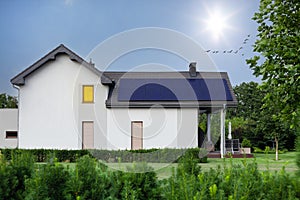 Modern house and beautiful garden with solar panels. Clear sky, sun photo