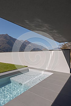 Modern house detail with swimming pool and garden. Reflection of water on the ceiling