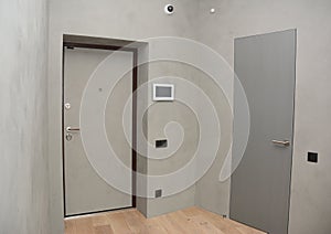 Modern house entrance metal door interior with security CCTV camera is mounted on the room wall with fire alarm system.