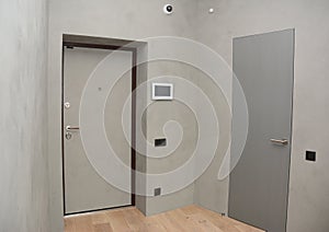 Modern house entrance metal door interior with security CCTV camera is mounted on the room wall with fire alarm system. photo