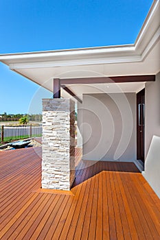 Modern house entrance from the side with wooden floor and a stone pillar like a brick wall