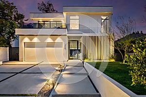 modern house exterior lighting on concrete driveway and lawning at night
