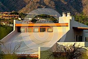 Modern house facade with white stucco and wood exterior and orange accent paint with slanted flat roof and windows